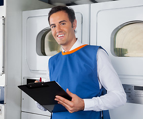 Image showing Male Helper Writing On Clipboard In Laundry