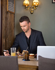 Image showing Businessman Messaging On Mobilephone While Having Meal