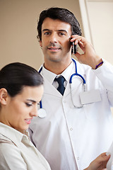 Image showing Doctor Answering Call While Standing With Colleague