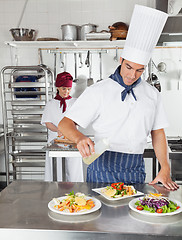 Image showing Chef Adding Oil To Dish In Kitchen