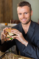 Image showing Businessman Holding Sandwich In Restaurant