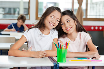 Image showing Schoolgirl Sitting With Female Friend At Desk In Classroom