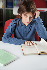 Image showing Schoolboy Reading Book At Table