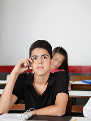 Image showing Teenage Schoolboy Looking Away While Sitting At Desk