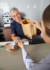 Image showing Salesman Collecting Cash While Passing Grocery Bag To Customer