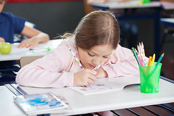 Image showing Schoolgirl Drawing In Book At Desk