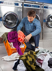 Image showing Man Putting Dirty Clothes In Basket at Laundromat