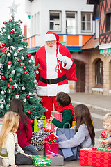 Image showing Children With Presents Looking At Santa Claus