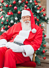 Image showing Santa Claus Sitting Against Decorated Christmas Tree