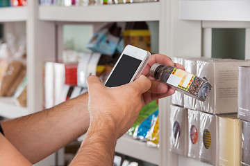 Image showing Man's Hand With Cellphone Scanning Product