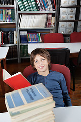 Image showing Schoolboy Sitting With Stacked Books At Table