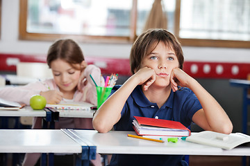 Image showing Bored Schoolboy Looking Away Sitting At Desk In Classroom