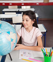 Image showing Schoolgirl Searching Places On Globe At Desk