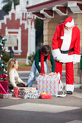 Image showing Santa Claus And Girl Looking At Boy Opening Gift