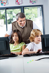 Image showing Teacher Looking At Schoolchildren Using Desktop Pc