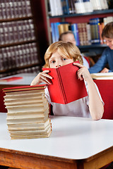 Image showing Schoolboy Peeking Through Book In Library