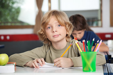 Image showing Portrait Of Schoolboy Writing In Book At Desk