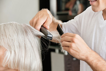 Image showing Hairstylist straightening woman's hair