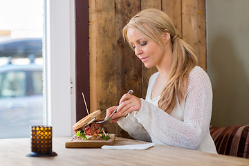 Image showing Young Woman Eating Burger At Restaurant