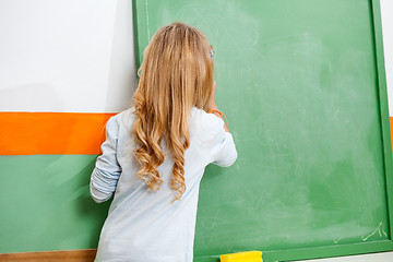 Image showing Little Girl Writing On Chalkboard In Classroom