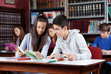 Image showing Teenage Classmates Reading Book In Library