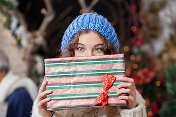 Image showing Woman Covering Face With Christmas Present At Store