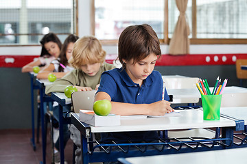 Image showing Schoolchildren Writing In Books At Desk