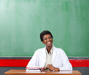 Image showing Happy Female Teacher Sitting At Desk In Classroom