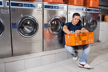 Image showing Man With Basket Of Clothes Sitting At Laundromat