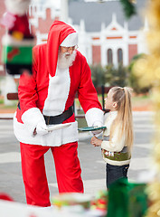 Image showing Santa Claus Offering Cookies To Girl