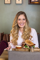 Image showing Young Woman With Burger At Table