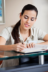 Image showing Female Receptionist Writing In Book