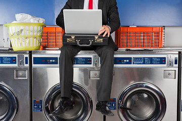 Image showing Businessman Using Laptop While Sitting On Washing Machine