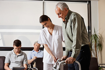 Image showing Man Being Assisted By Nurse To Walk Zimmer Frame