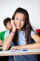 Image showing Happy Schoolgirl Sitting At Desk In Classroom