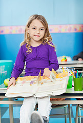 Image showing Girl With Book Sitting On Desk In Classroom