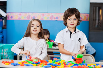 Image showing Cute Friends Playing With Blocks At Desk In Kindergarten