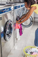 Image showing Woman Loading Washing Machine With clothes