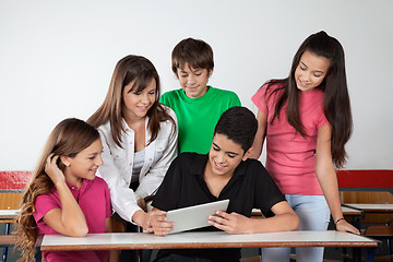 Image showing Teenage Schoolboy Showing Tablet To Classmates At Desk
