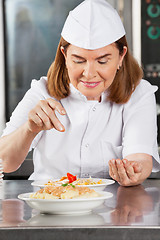 Image showing Female Chef Adding Spices To Dish