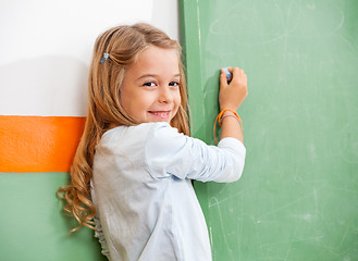 Image showing Girl Writing On Green Chalkboard In Classroom