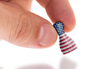 Image showing Hand holding wooden pawn, flag painting, selective focus