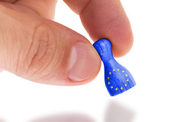 Image showing Hand holding wooden pawn, flag painting, selective focus