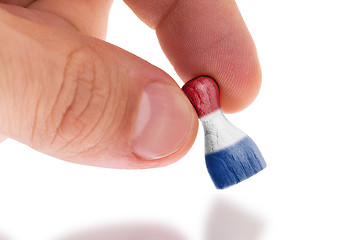 Image showing Hand holding wooden pawn, flag painting, selective focus