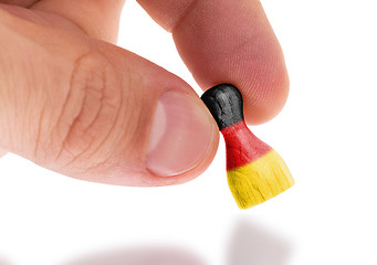 Image showing Hand holding wooden pawn, flag painting, selective focus