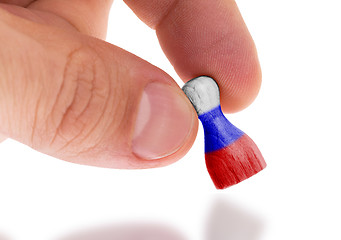 Image showing Hand holding wooden pawn, flag painting, selective focus