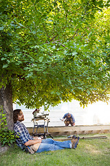 Image showing Carpenter With Eyes Closed Leaning On Tree Trunk