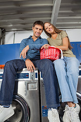 Image showing Couple With Laundry Basket Sitting On Washing Machines