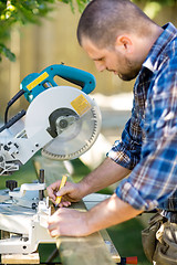 Image showing Carpenter Marking On Wood With Pencil At Table Saw