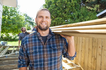 Image showing Happy Carpenter And Coworker Carrying Lumbers At Construction Si